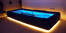 a floatation tank with lights lighting up the water and bottom of the tub
