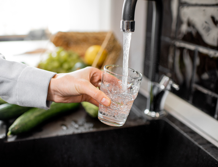 A person filling up a glass from a tap