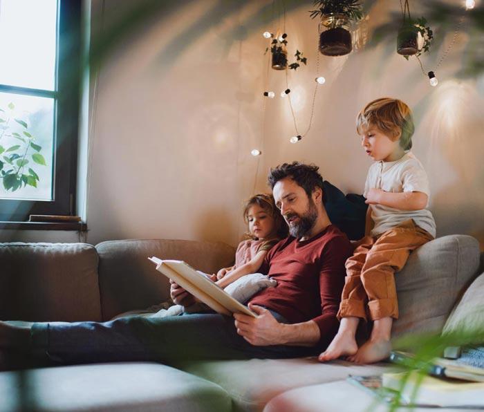 A man reading a book to his children 
